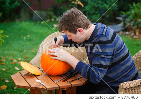 Young man making halloween pumpkin 8776460