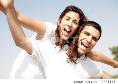 Smiling young couple holding hands eachother while piggyback Smiling young couple holding hands eachother while piggyback 8781143