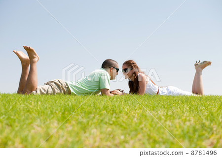 Playful young couple laying on a grass lawn Playful young couple laying on a grass lawn 8781496