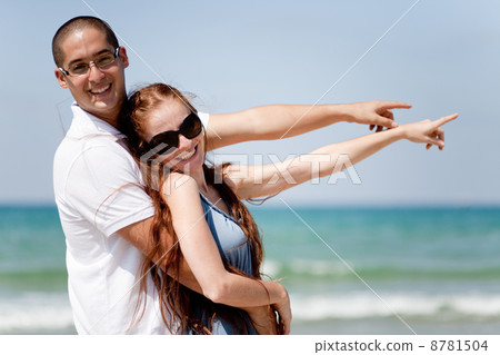 Couple smiling and pointing at the sea Couple smiling and pointing at the sea 8781504
