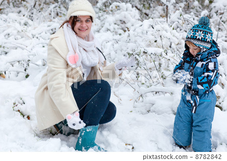 Mother and toddler boy having fun with snow on winter day 8782842