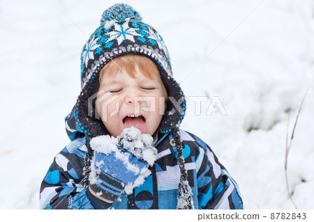 Adorable toddler boy having fun with snow on winter day 8782843