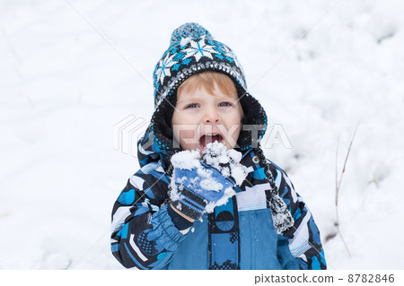 Adorable toddler boy having fun with snow on winter day 8782846