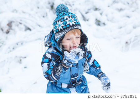 Adorable toddler boy having fun with snow on winter day 8782851