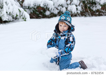 Adorable toddler boy having fun with snow on winter day 8782854