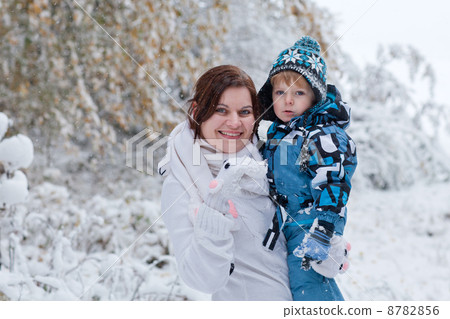 Mother and toddler boy having fun with snow on winter day 8782856