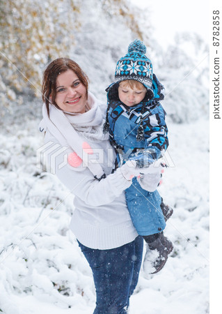 Young woman and her little son having fun with snow in winter fo 8782858