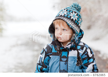 Adorable toddler boy having fun with snow on winter day 8782865
