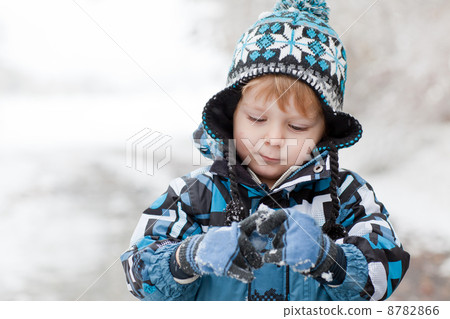 Adorable toddler boy having fun with snow on winter day 8782866