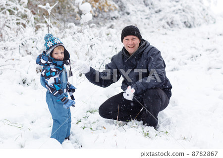 Father and toddler boy having fun with snow on winter day 8782867