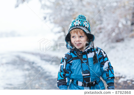 Adorable toddler boy having fun with snow on winter day 8782868