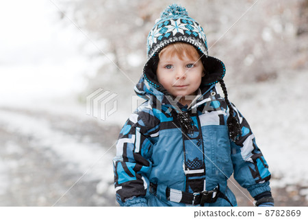 Adorable toddler boy having fun with snow on winter day 8782869