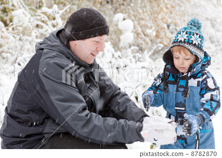 Father and toddler boy having fun with snow on winter day 8782870