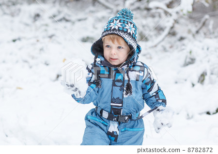 Adorable toddler boy having fun with snow on winter day 8782872