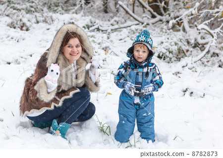 Mother and toddler boy having fun with snow on winter day 8782873