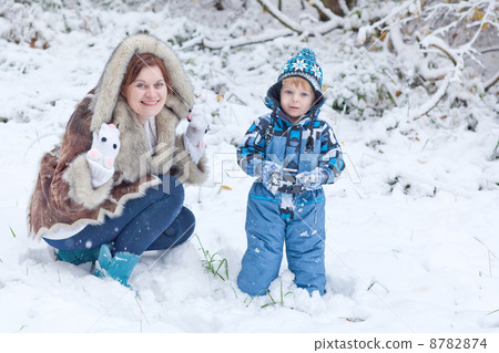 Mother and toddler boy having fun with snow on winter day 8782874