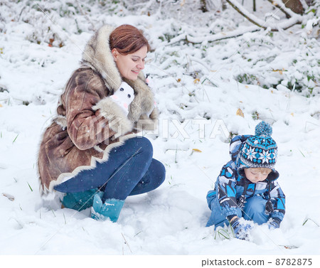 Mother and toddler boy having fun with snow on winter day 8782875