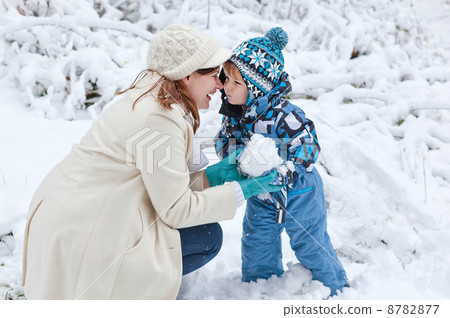 Young woman and her little son having fun with snow on winter da 8782877