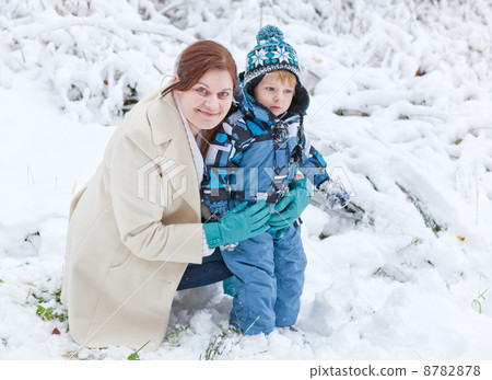 Young woman and her little son having fun with snow on winter da 8782878