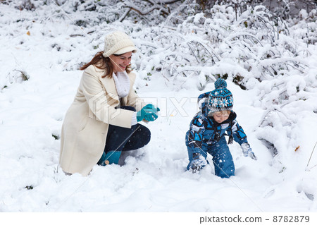 Mother and toddler boy having fun with snow on winter day 8782879