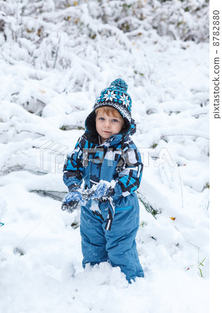 Adorable toddler boy having fun with snow on winter day 8782880