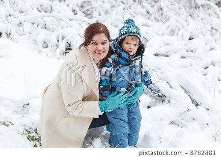 Young woman and her little son having fun with snow in winter fo 8782881