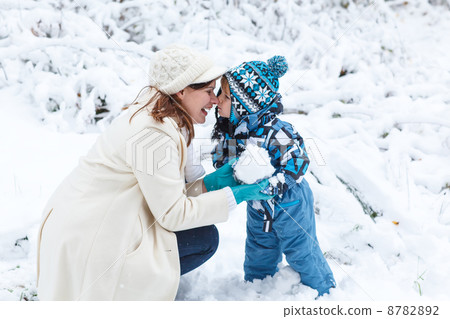 Mother and toddler boy having fun with snow on winter day 8782892