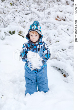Adorable toddler boy having fun with snow on winter day 8782894