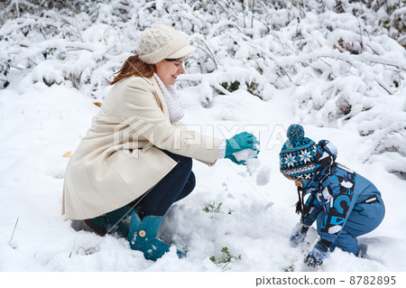 Mother and toddler boy having fun with snow on winter day 8782895