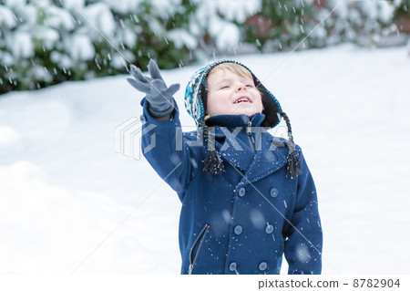Little toddler boy having fun with snow outdoors on beautiful wi 8782904