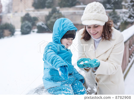 Mother and toddler boy having fun with snow on winter day 8782908