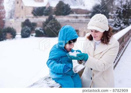 Mother and toddler boy having fun with snow on winter day 8782909