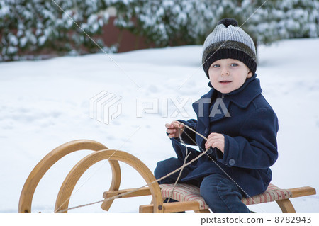 Lovely little boy on ancient sledge on winter day 8782943