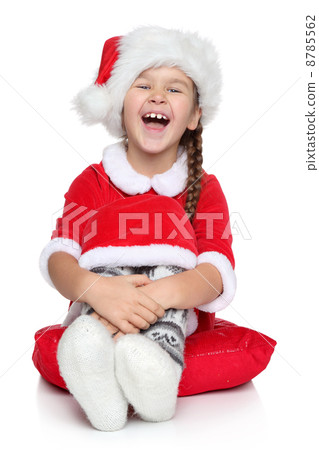 Happy little girl in Santa hat laughs on a white background 8785562
