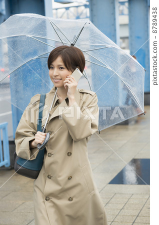 A woman talking on the phone while holding an umbrella 8789438