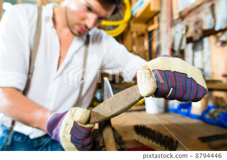 Young man sharpening tools in mountains hut 8794446