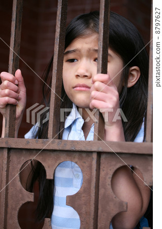 Little girl standing behind iron bars Little girl standing behind iron bars 8797627