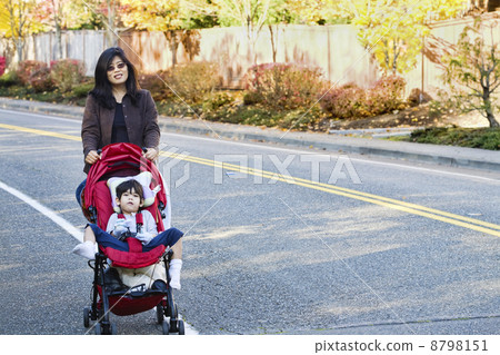 Mother pushing her son in the stroller 8798151