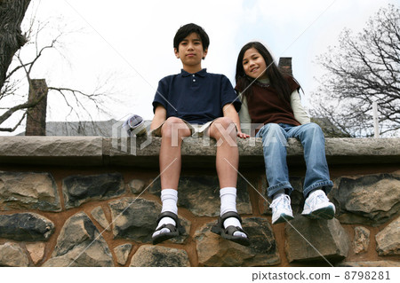 Two children sitting on rock ledge Two children sitting on rock ledge 8798281