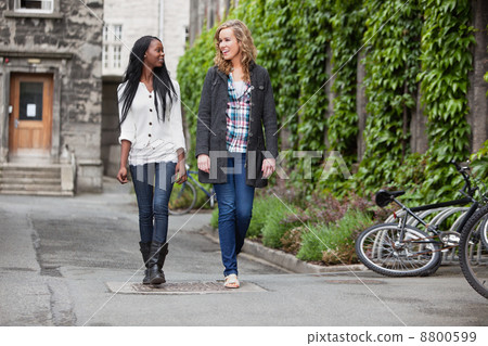 Young female friends having a chat while walking 8800599