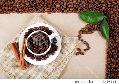 Cup with coffee beans and cinnamon sticks on sackcloth. 8816551