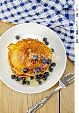 Flapjacks with blueberries and a fork on a board 8818434
