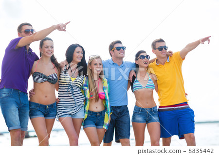 group of friends pointing somewhere on the beach 8835442