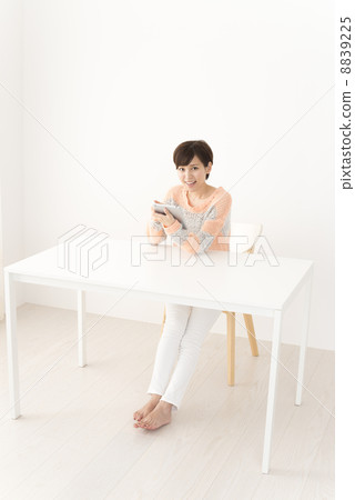 A woman in casual attire looking up the net with a tablet 8839225