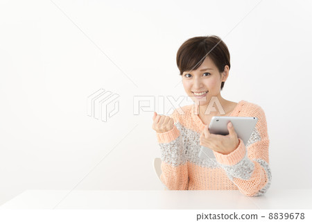 A woman in casual attire looking up the net with a tablet A woman in casual attire looking up the net with a tablet 8839678