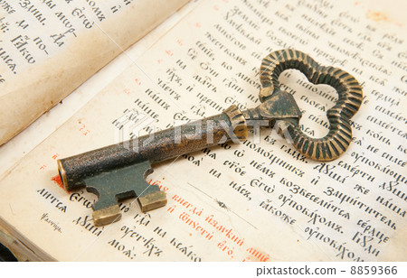 Closeup of key placed on vintage bible 8859366