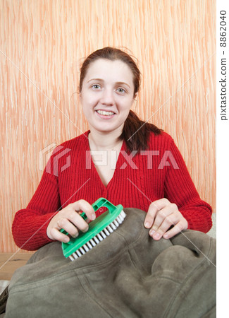 Woman cleaning a sheepskin with whisk broom 8862040