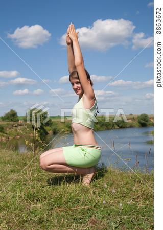 girl exercising on meadow against river 8863672