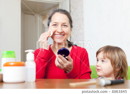 grandmother with granddaughter puts facepowder 8863845