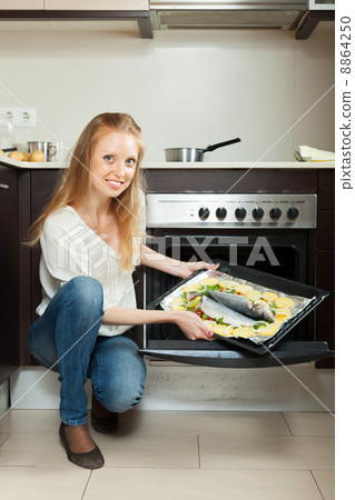 woman cooking fish in oven woman cooking fish in oven 8864250